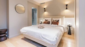 A modern bedroom with a large bed, bedside lamps, and a mirror on the wall. - Splendeur de 187m² Climatisé au Cœur de Paris (Paris)