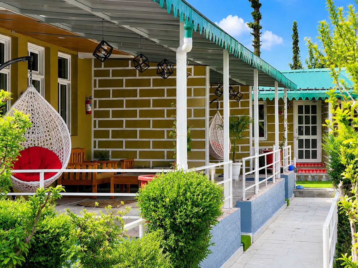 A covered outdoor seating area with hanging chairs, a brick wall, and a door.