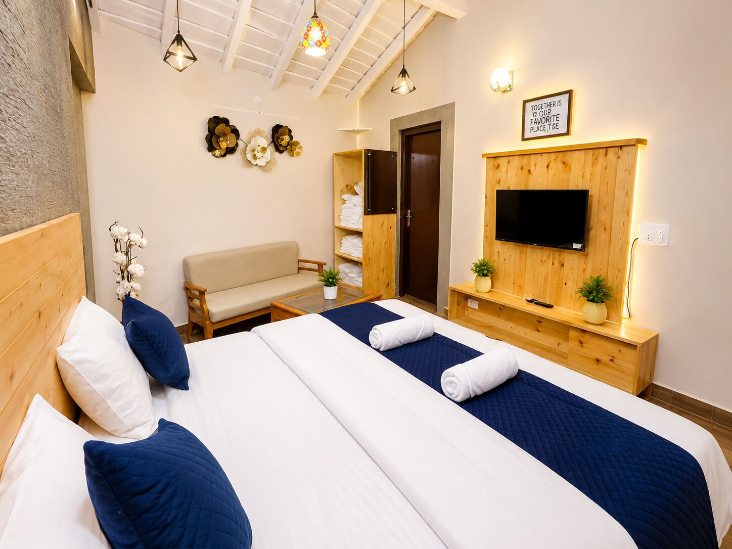 A hotel room with a bed, a sofa, a TV, and a wall with a sign.