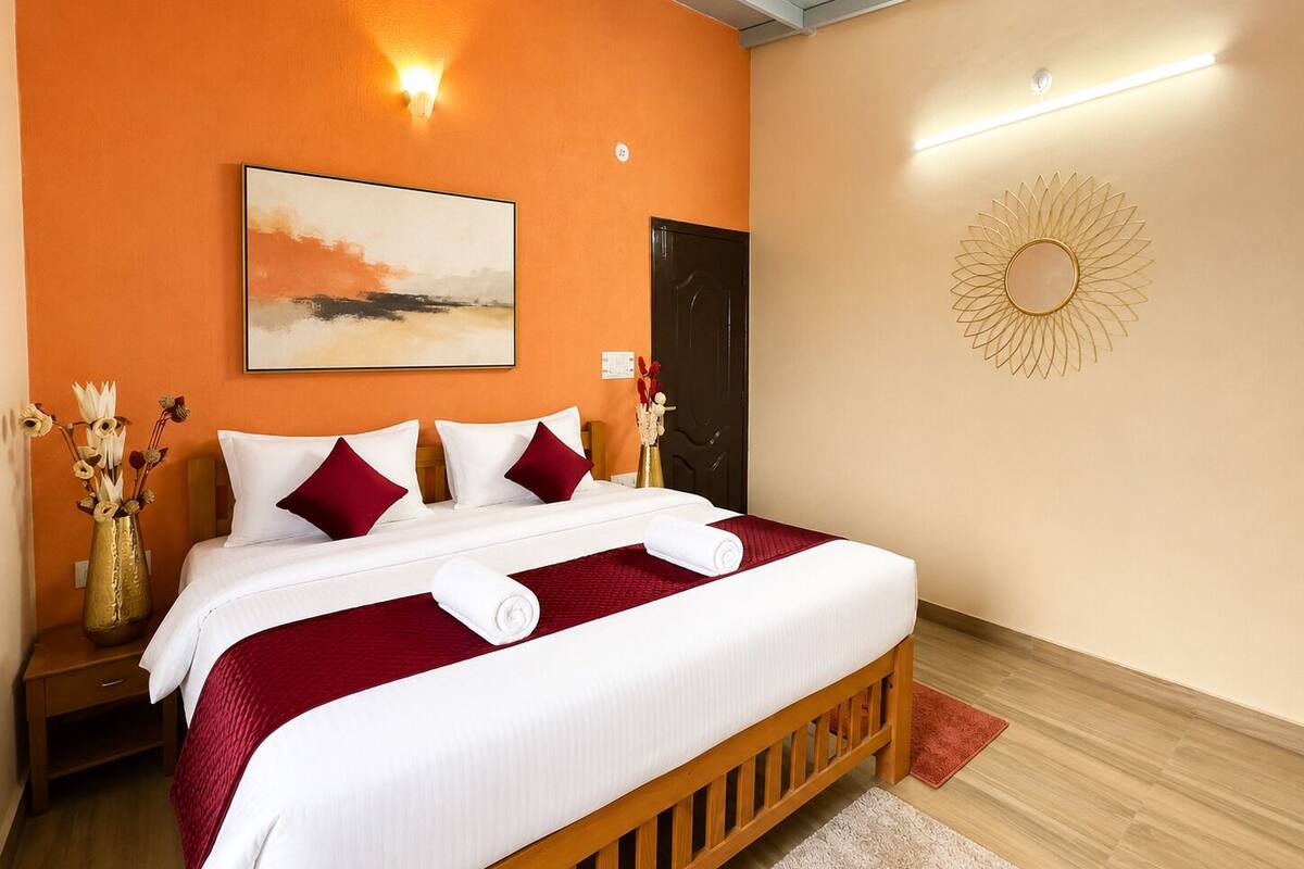 A hotel room with a bed, a painting, a wall decoration, and a nightstand with a vase.
