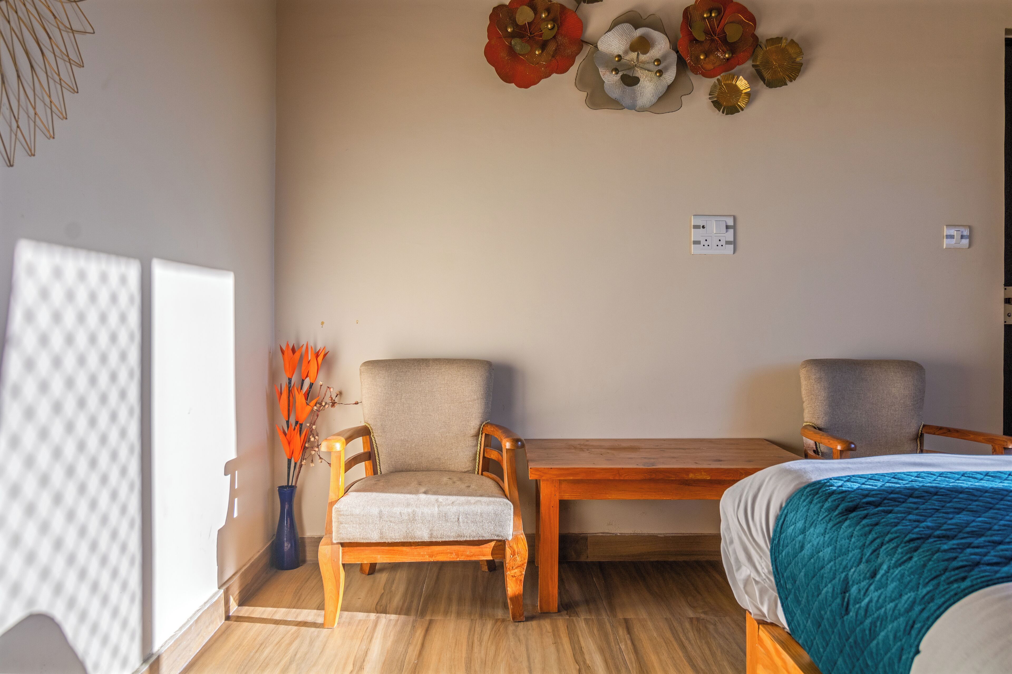 A room with a wooden bed, a wooden table, two chairs, and a wall-mounted light fixture.