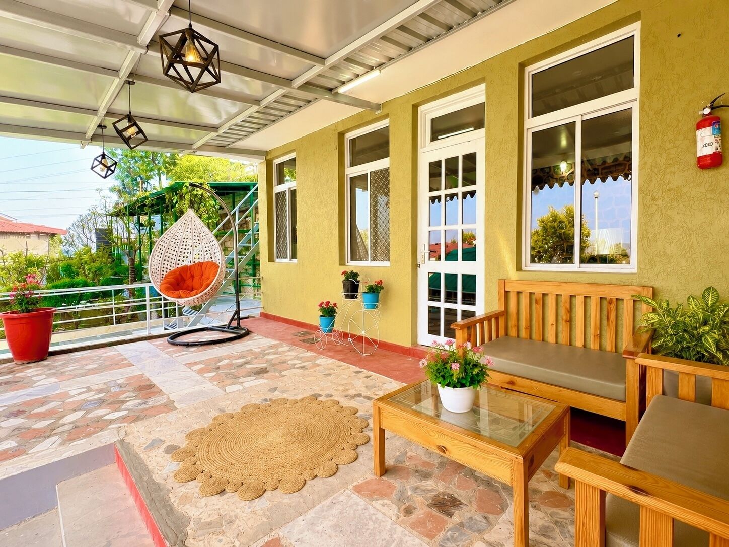 Un espacio al aire libre cubierto con un banco de madera, una silla colgante y plantas en macetas.