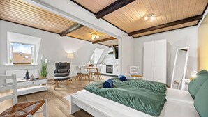 Ein modernes Schlafzimmer im Loftsstil mit einem großen Bett, einem Schreibtisch und einer Essecke.