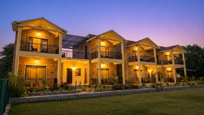 A multi-story hotel with balconies, stone facade, and outdoor lighting. - Achal Bagh – Boutique Stay Abu Road (Abu Road)