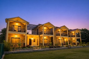 A multi-story hotel with balconies, stone facade, and outdoor lighting.