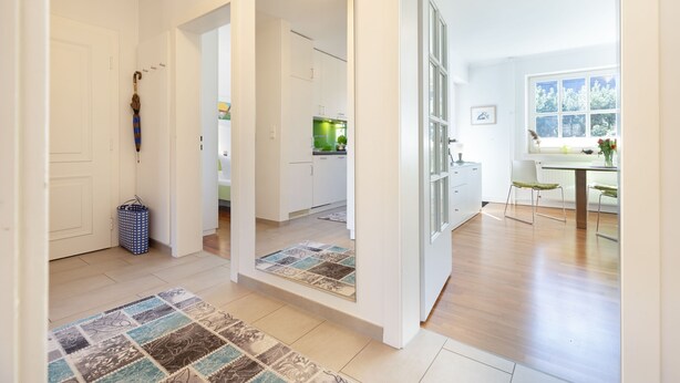 Ein modernes Interieur mit Küche, Essbereich und einem Flur, der zu einer Tür führt.