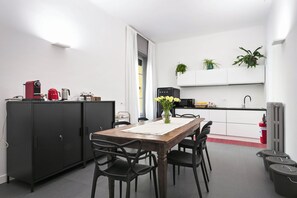 Une cuisine moderne avec une table à manger, des chaises, une machine à café et des plantes en pot.