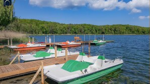 A dock with several small boats, a wooden pier, and a forested shoreline.