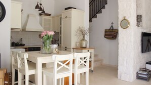 A kitchen with white cabinets, a dining table with chairs, a vase with flowers, and a staircase leading to another level. - Seafront Villa Marella (Milna)