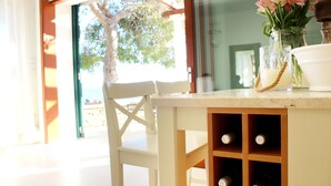 A table with a vase of flowers, a candle, and a wine bottle. - Seafront Villa Marella (Milna)