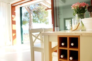 A table with a vase of flowers, a candle, and a wine bottle. - Seafront Villa Marella (Milna)