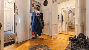 Um corredor com um porta-roupas, um espelho e uma estátua de cavalos.