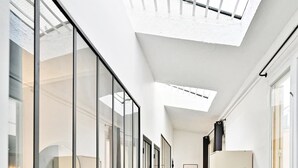 A modern hallway with large windows, a skylight, and a bench. - Loft moderne 2BR - Cœur de Paris A/C portable (Paris)