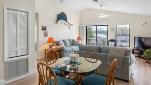 A spacious living room with a glass dining table, two sofas, and a TV. - Joe`s Beach House | Walk to IRB | Family Friendly (Indian Rocks Beach)