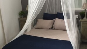 Un lit à baldaquin, une table de chevet avec une lampe et une plante en pot.