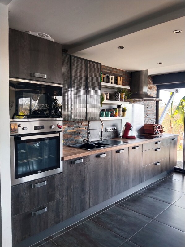 A modern kitchen with a built-in oven, a sink, and wooden cabinets. - Villa swimming pool urt (Urt)