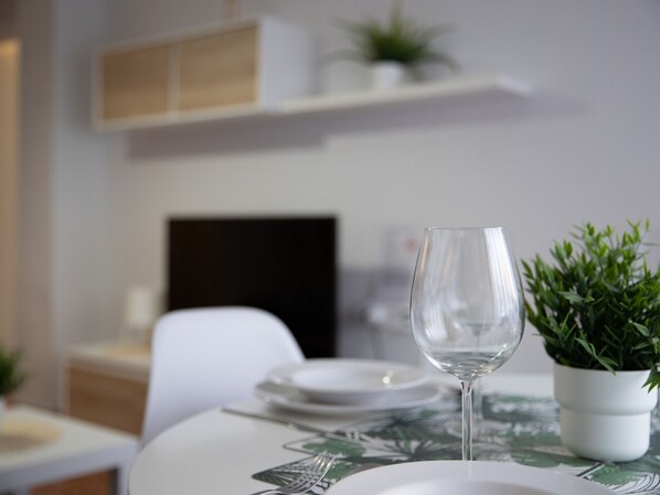 A dining table with a clear glass, a white plate, and a small potted plant.