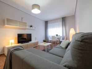 A modern living room with a sofa, TV, and a dining area with a table and chairs.
