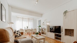 Un salon moderne comprenant un canapé, une table basse, un téléviseur et un coin repas avec des chaises et une table.