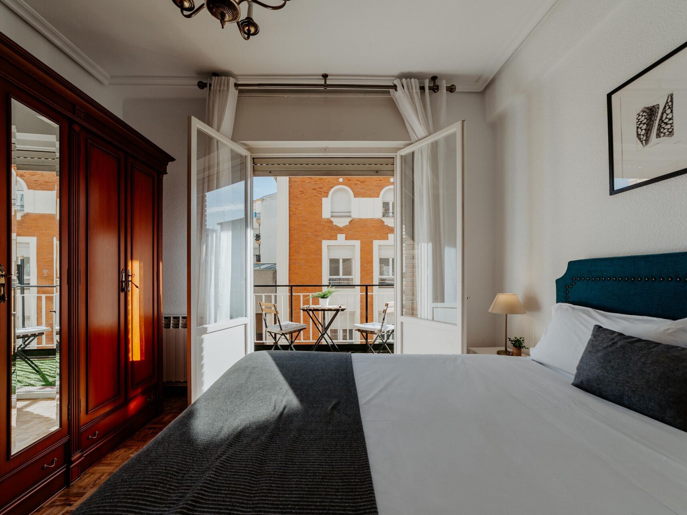 A bedroom with a large bed, a view of a courtyard, and a balcony.