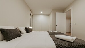A hotel room with a large bed, a bedside table, a lamp, a door, and a view of the hallway. - Charming apartment in Logroño for 4, includes Wi-Fi (Logroño)