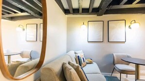 En moderne stue med en sofa, et rundt bord og et spejl.