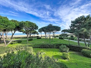 Un jardín ajardinado con setos y árboles bien cuidados, un sendero y vistas a la playa.