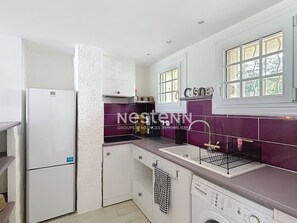 Una cocina compacta con armarios blancos, lavavajillas integrado y ventana con vistas.