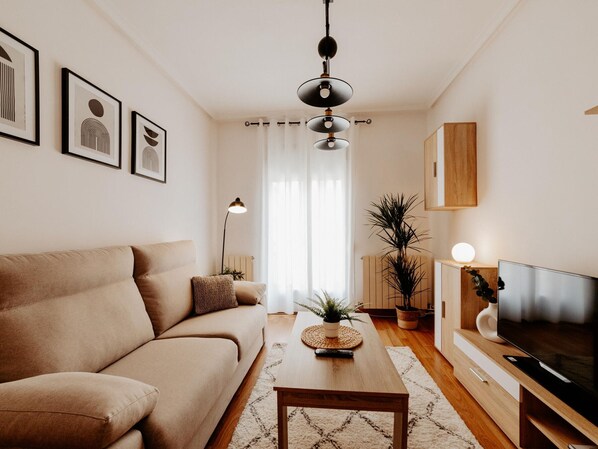 Ein modernes Wohnzimmer mit einer Couch, einem Couchtisch, einem Fernseher und Kunstwerken an der Wand.