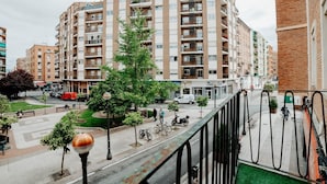 A multi-story residential building with balconies, a pedestrian walkway, and a street with parked vehicles. - Comfortable Apartment with Terrace in Logroño (Logroño)
