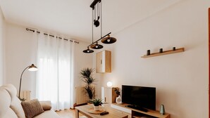 A living room with a sofa, a coffee table, a TV, and a plant. - Comfortable Apartment with Terrace in Logroño (Logroño)