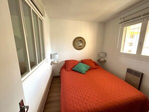 A bedroom with a large bed, two bedside tables with lamps, a mirror, and a window. - Air-conditioned apartment with parking, close to beach and shops (Argelès-sur-Mer)