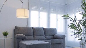 A modern living room with a grey sofa, a small side table, and a floor lamp. - Renovated Apartment in Central Logroño with Private Parking (Logroño)