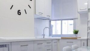 A modern kitchen with white cabinets, a window, and a dining area with a table and chairs. - Renovated Apartment in Central Logroño with Private Parking (Logroño)