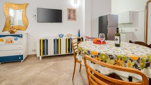 Ett modernt kök med ett matbord, stolar, en TV och ett kylskåp.