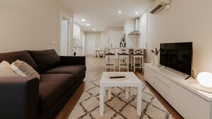 A modern living room with a sofa, a coffee table, a TV, and a dining area in the background. - Central Renovated Apartment with Wi-Fi in Logroño (Logroño)