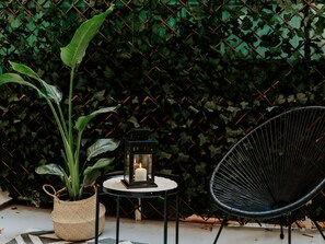 A round table with a candle and a lantern, a black chair, and a potted plant against a green leafy background. - Modern Elegance in the Heart of Logroño for 6 People (Logroño)