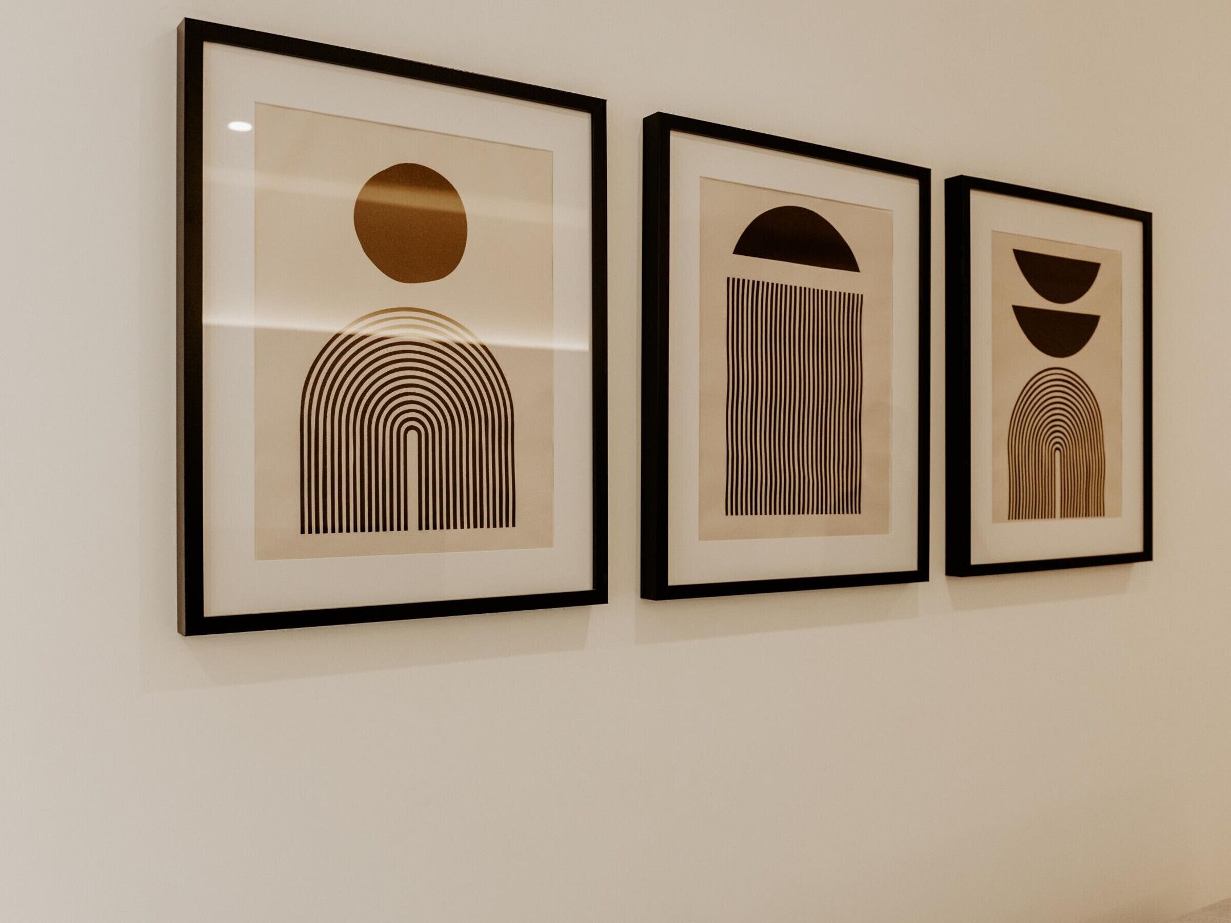 Trois œuvres d’art abstraites encadrées sont accrochées à un mur.