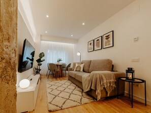 Una sala de estar moderna con un sofá, una mesa de centro, un televisor y un comedor con una mesa y sillas.