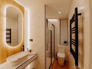 A modern bathroom with a large oval mirror, a white sink, and a glass shower enclosure. - Modern Elegance in the Heart of Logroño for 6 People (Logroño)