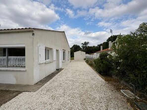 Ein befestigter Weg führt zu einem weißen Gebäude mit Fenstern und einem Balkon.