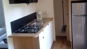 A compact kitchen with a gas stove, a coffee maker, and a stainless steel refrigerator. - Family Mobile Home with Terrace - 4 People (Marcilly-sur-Vienne)