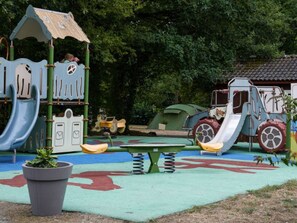 Un parque infantil con tobogán, estructura de escalada y una mesa de juegos.