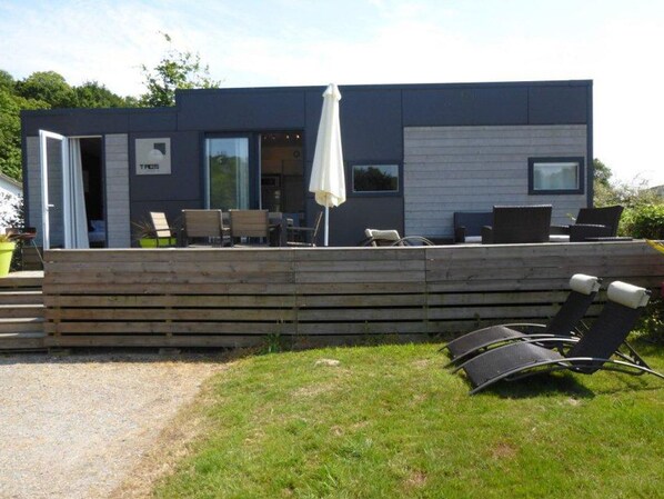 Een modern huis met terras, zitplaatsen buiten en een grote parasol.