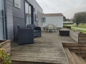 Een terras met buitenmeubilair, waaronder stoelen en een bank, en een kleine tafel.