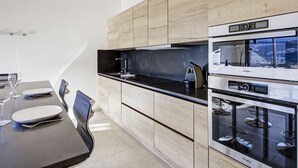 A modern kitchen with a dining area, featuring a black countertop, stainless steel appliances, and light wood cabinetry. - Apartment 5 Guests Banyuls-sur-Mer with Parking and Air Conditioning (Banyuls-sur-Mer)