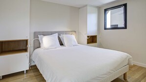 A bedroom with a bed, bedside tables, a nightstand, a window, and built-in shelving. - Apartment 5 Guests Banyuls-sur-Mer with Parking and Air Conditioning (Banyuls-sur-Mer)