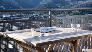 A wooden table with a book and glasses on a balcony with a mountain view. - Apartment 5 Guests Banyuls-sur-Mer with Parking and Air Conditioning (Banyuls-sur-Mer)