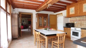 Uma cozinha com armários de madeira, chão de azulejos e um espaço de jantar com cadeiras de madeira.