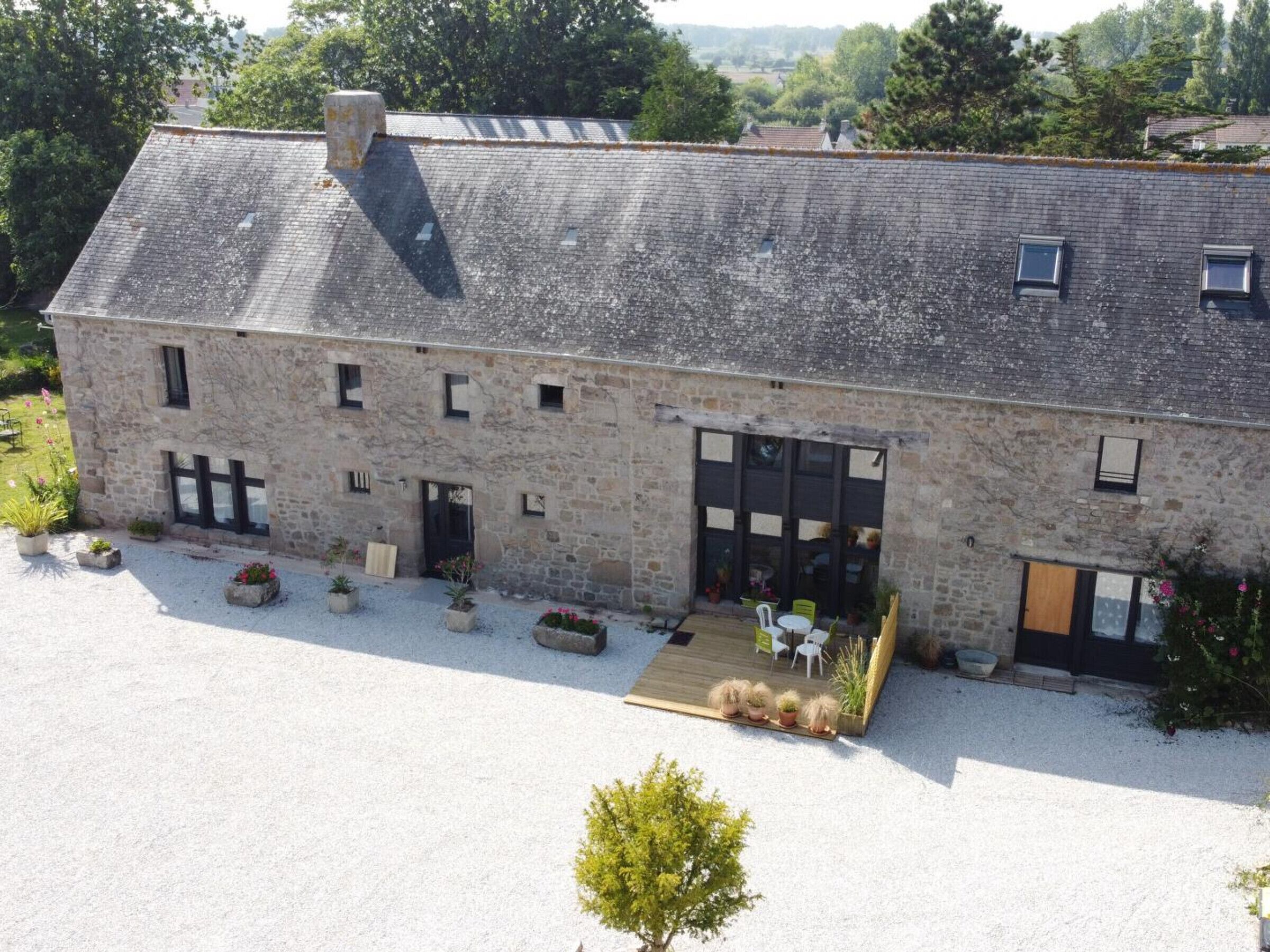 A stone building with a large garage door, outdoor seating, and a gravel driveway.